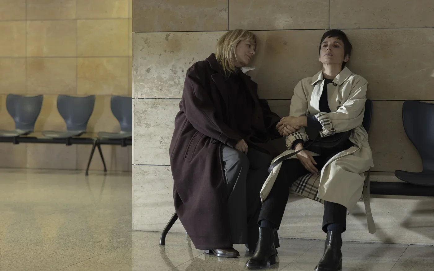 Fotograma de «Hermanas»: dos mujeres conversan sentadas en un banco de una sala de espera.